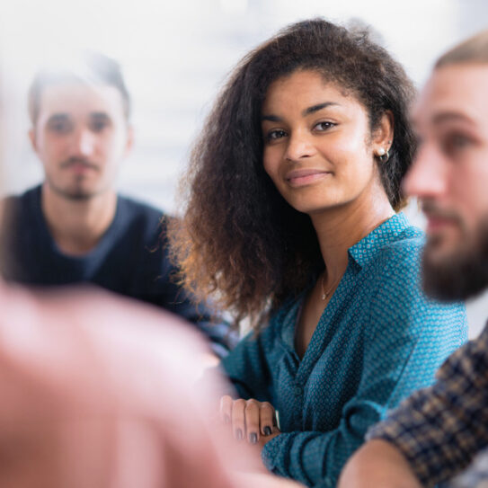 Meeting at the startup office . A working group meets to study a new project. Focus on a beautiful young black woman looking at camera