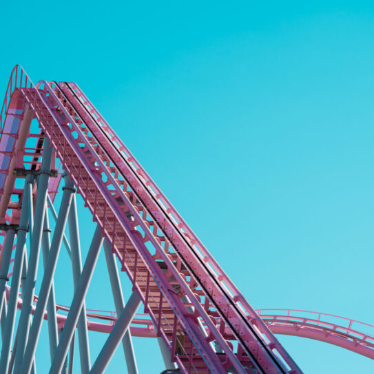 Pink pastel looping roller coaster on blue sky sunny day background.