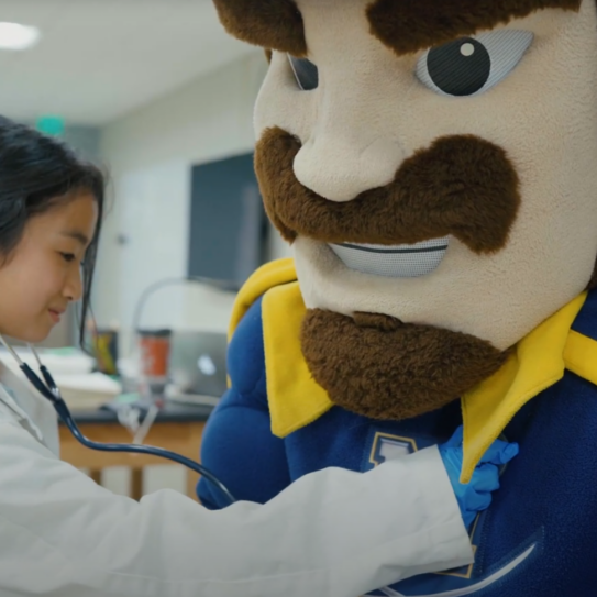 young lady pretending to hear the heartbeat of the school mascot