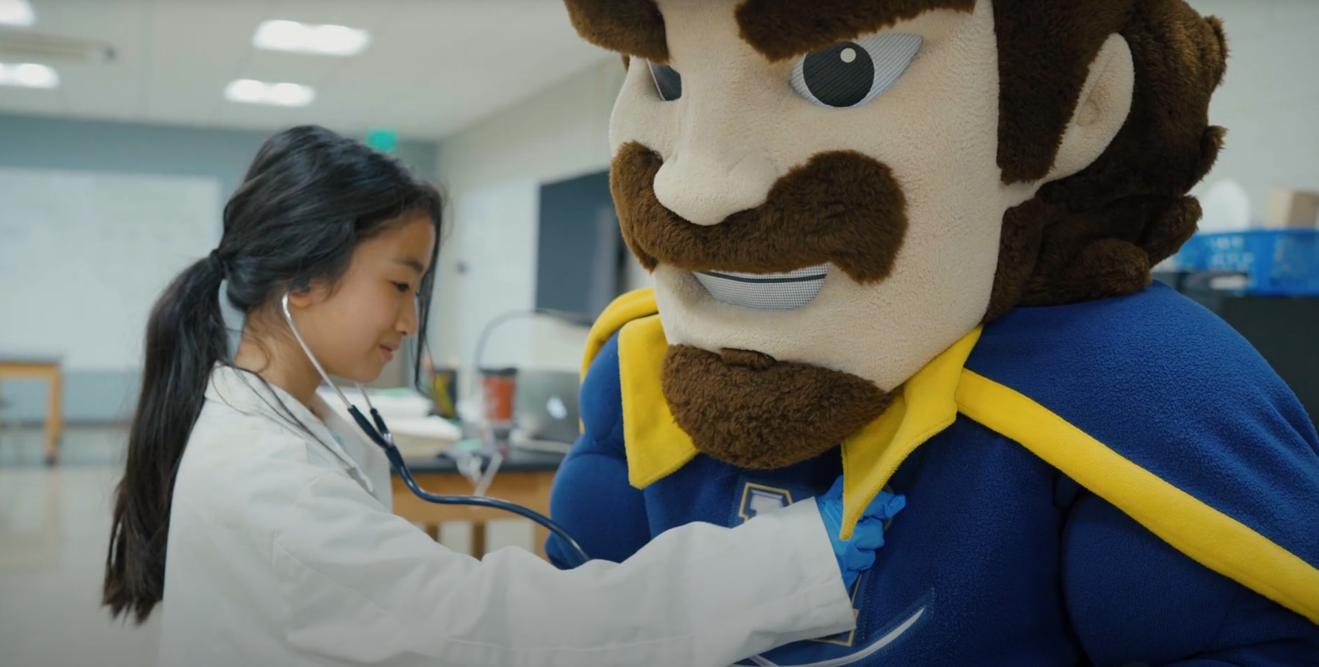 young lady pretending to hear the heartbeat of the school mascot