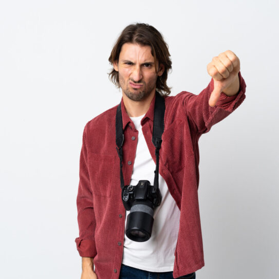 Young photographer man isolated on white background showing thumb down with negative expression