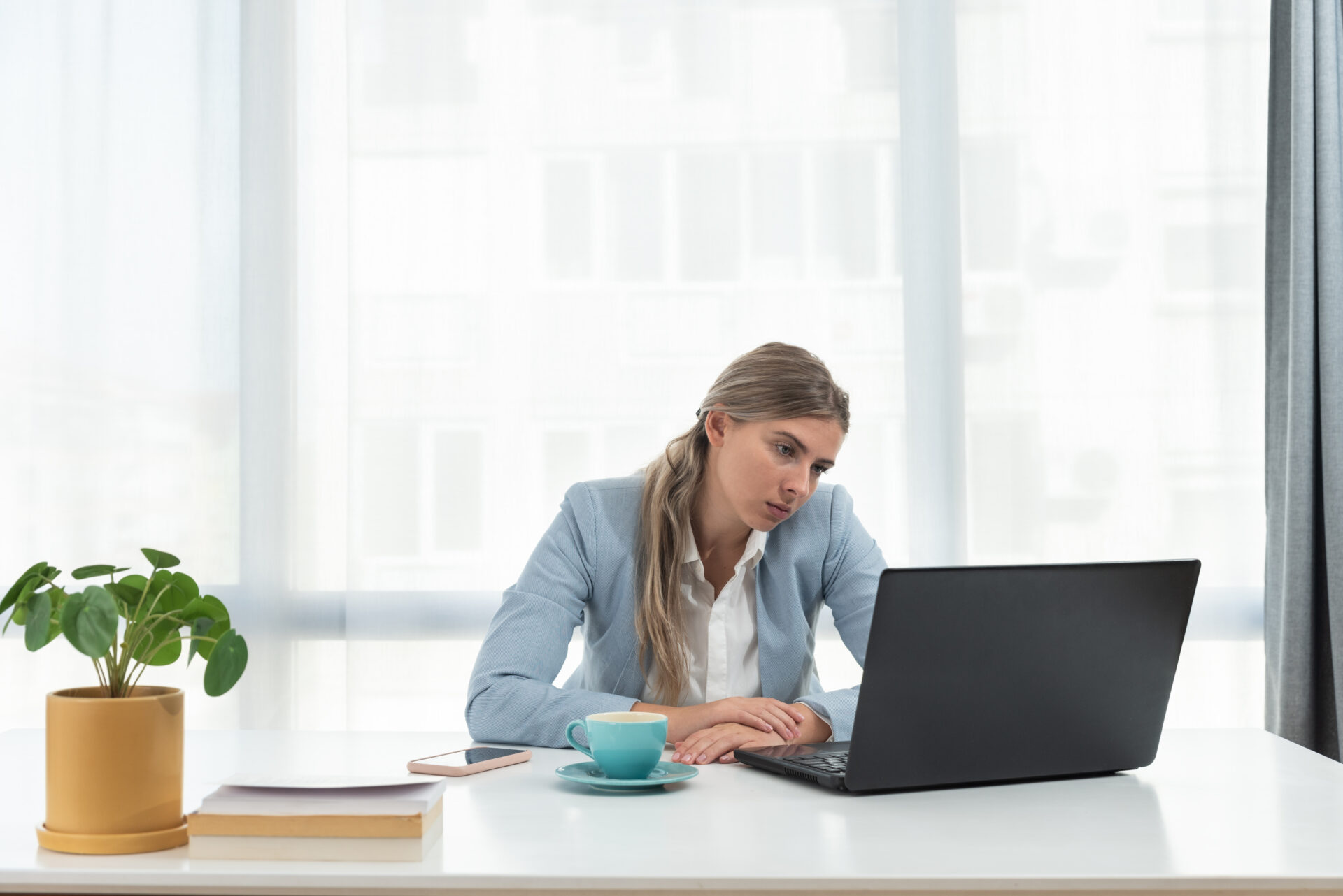 Young frustrated business woman office worker trying to concentrate for her work while she sitting in the company office with old laptop computer and slow internet connection.