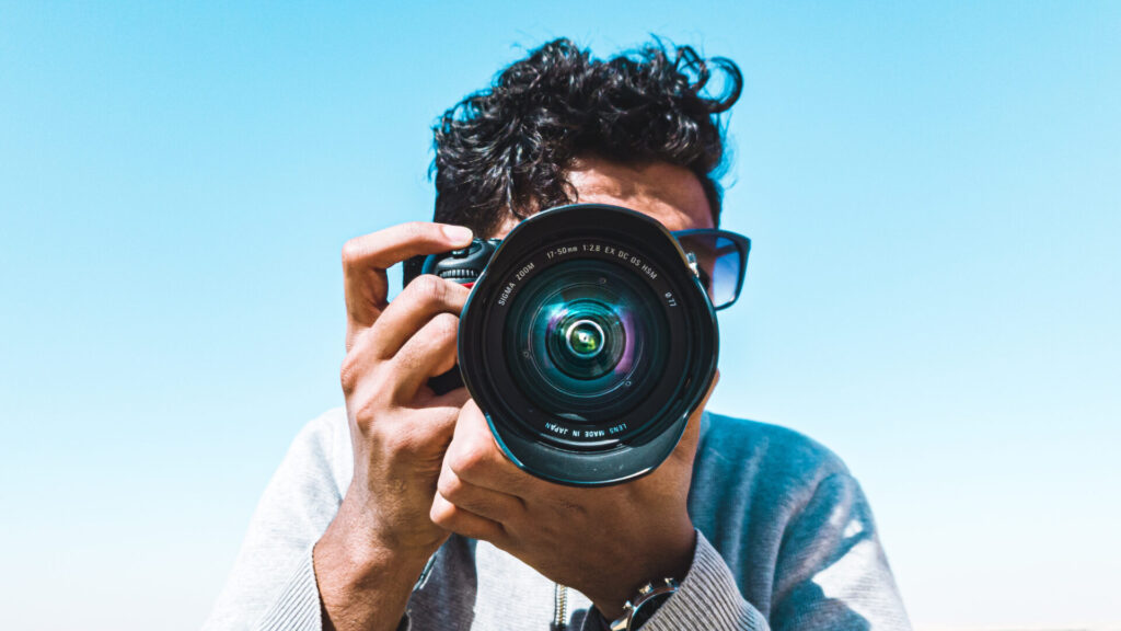 Image of a man holding up a camera pointed directly at the viewer.