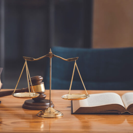 Lawyer's desk in the office with scales, books, and a gavel sitting atop the desk.