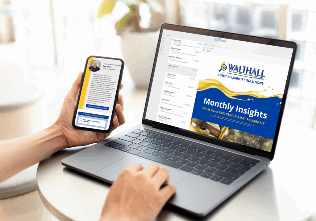 A person sits at a table using a laptop and holding a smartphone. Both screens display emails from WALTHALL Asset Reliability Solutions, with the laptop showing a Monthly Insights newsletter.