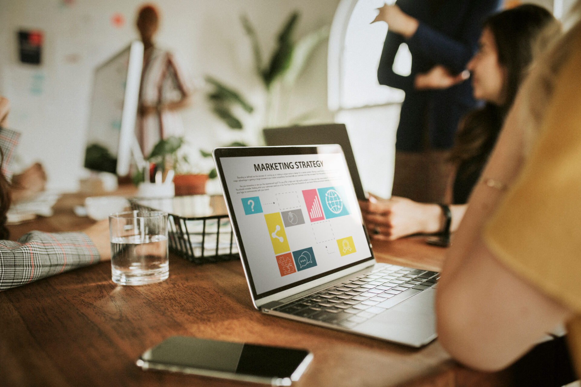 Closeup of a person's laptop in a meeting with a marketing partner. The screen has several icons on it with the heading Marketing Strategy