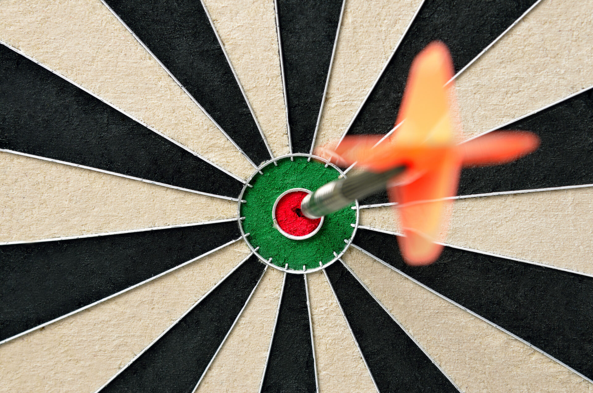 A red dart with orange flights sticks in the bullseye of a black and white dartboard, shot from above to emphasize precision. Visually signifying brand clarity.